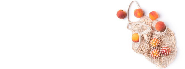 Flying fresh peaches outside eco bag on white background