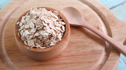 Rolled oat in wooden bowl  on blue wooden table background. healthy food concept.