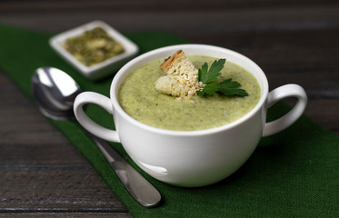 , garlic, sesame and olive oil, and coconut milk soup. served in a white ceramic plate on a dark brown wooden board using green textileVegetarian cream of broccoli, potato, onion