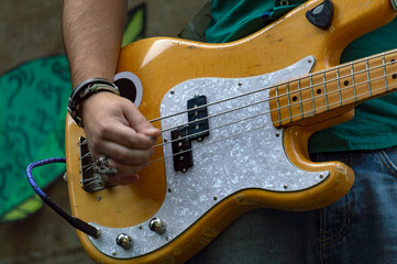 Man in  light shirt plays bass guitar. Front view.