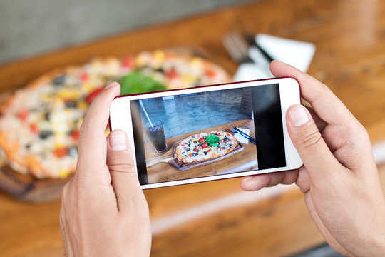 Male hand making a photo of pizza, with a mobile phone, close up, horizontal