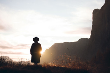 Hipster Girl in a Black Coat Walks in Alpine Mountains