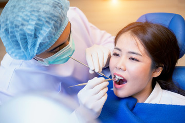 Young man dentist who treats teeth of young woman patient.