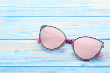 Modern sunglasses on blue wooden table