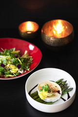 Delicious goat cheese with asparagus and colorful green salad with raspberries on dark background