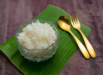Thai jasmine rice in bowl with a spoon and fork on wooden table