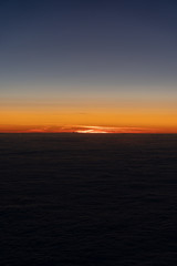 Naklejka na ściany i meble Sonnenuntergang aus Flugzeug über den Wolken