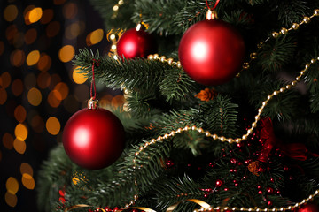 Obraz na płótnie Canvas Christmas fir tree with ornaments on blurred lights background