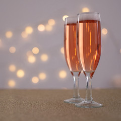 dos copas de champaña en una mesa con mantel dorado y luces bokeh de fondo 