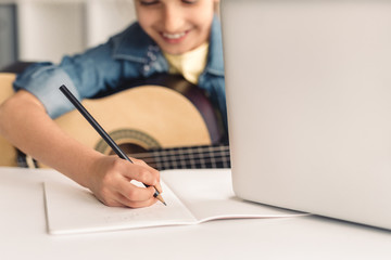 Kid making notes during online music lesson