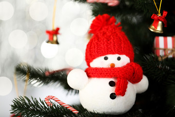 Christmas fir tree with small snowman on blurred lights background