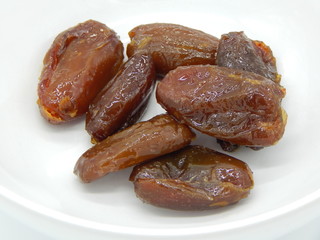 Sweet dried dates on a plate, as closeup isolated on white background