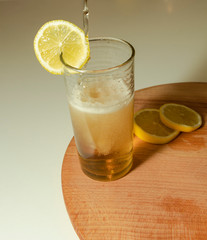 Lemonade in the glasses with lemon slice and wooden board. Pour the lemonade.  White background.