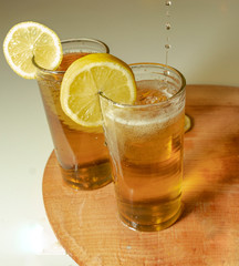 Lemonade in the glasses with lemon slice and wooden board. Pour the lemonade.  White background.