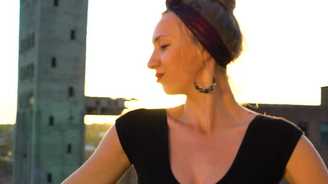 Young girl performing on industrial roof at sunset