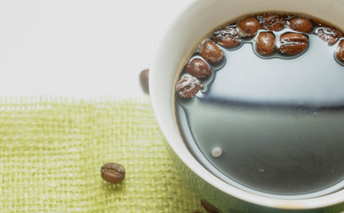The cup of black coffee with coffee beans with wooden spoon. White background.