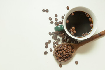 The cup of black coffee with coffee beans with wooden spoon. White background.