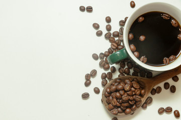 The cup of black coffee with coffee beans with wooden spoon. White background.