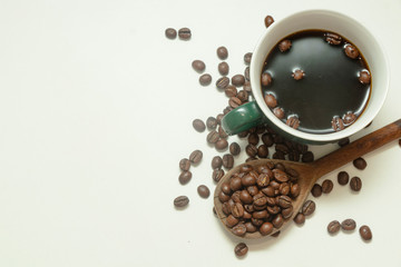 The cup of black coffee with coffee beans with wooden spoon. White background.