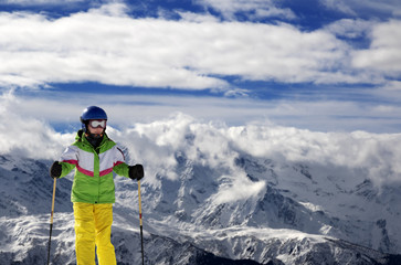 Fototapeta na wymiar Young skier with ski poles in snowy mountains at sun winter day