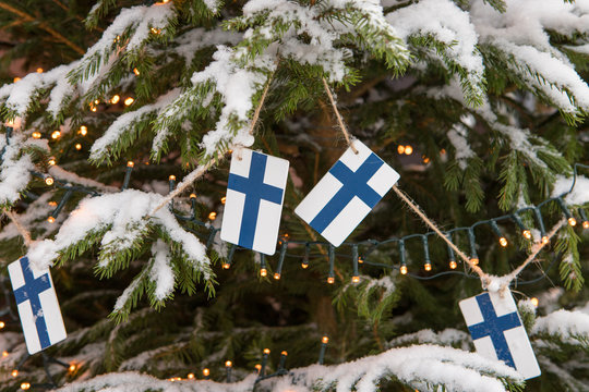 Decoration of a snow-covered Christmas tree of garlands and Finnish flags