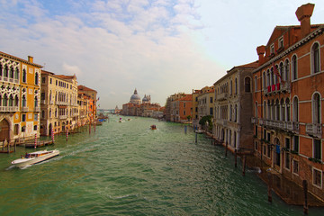 Landscape of Grand Canal with turquoise water at sunny day. Medieval colorful buildings and palazzo along the canal. Basilica Santa Maria della Salute in the background. Travel and tourism concept