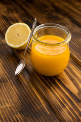Lemon kurd in the glass jar on the brown wooden background. Location vertical. Copy space.