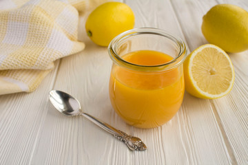 Lemon kurd in the glass jar on the white  wooden background. Closeup.