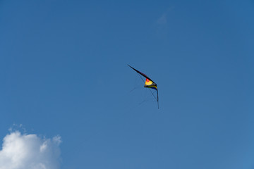 A colorful kite flying in the air, the blue sky in the background