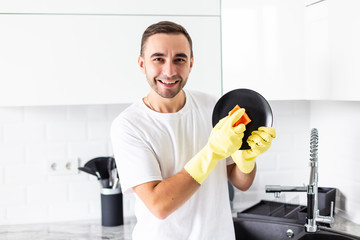 Smiling handsome man washing dish in the kitchen