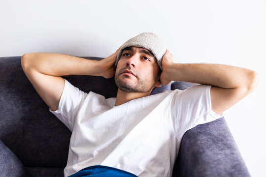 Sick man have faver lying on sofa checking his temperature under a blanket at home in the living room