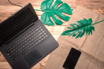Flat lay, top view office table desk. Workspace with keyboard, office supplies, pencil, and green leaf on wooden background