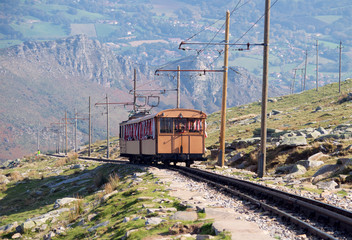 Obraz premium The train on the railway high in the mountains descends into the valley
