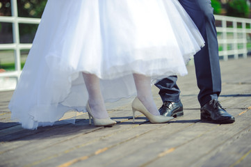 Obraz na płótnie Canvas The bride shows white wedding shoes. Wedding detail. Close up.