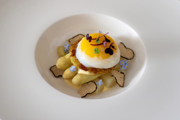 Fine dining poached egg with white asparagus, truffles and béarnaise sauce