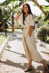 stylish young attractive woman dressed in a long linen dress with a hat photographed in the summer...