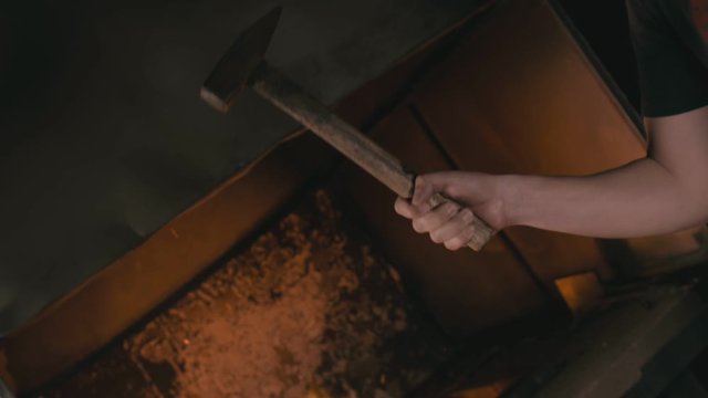Forge workshop. Smithy manual production. Hands of smith with hammer hit on glowing hot metal, on the anvil, the forging process. Blacksmith makes iron products for manufacture of fireplace, stove.