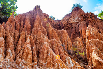 High red clay rocks and cliffs washed by winter rains and surface water flows. Clay quarry, mines landscape scene in Cilento and Vallo di Diano National Park in Campania, Italy