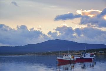 Two fishing boats in the bay during the afternoon with a cloudy sky 