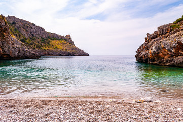 Fototapeta na wymiar Unique white pebbles lying on amazing Cala Bianca beach surrounded by rocks and Tyrrhenian sea bay with crystal clear deep water full of underwater life. Cala Bianca beach in Campania, Italy