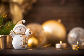 Christmas golden decorations and snowman on dark wooden backgrou