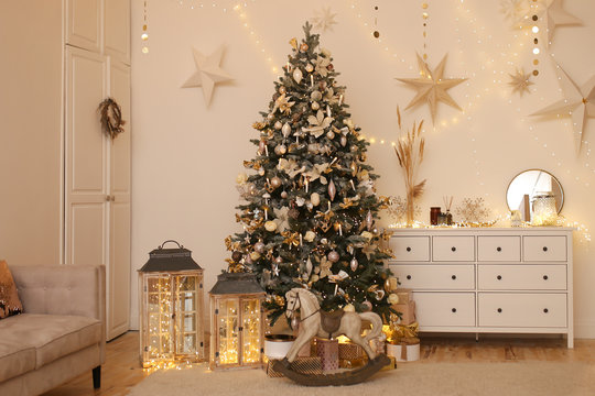 Christmas interior. Beautiful high decorated Christmas tree, garlands, stars, horse, gifts and bokeh