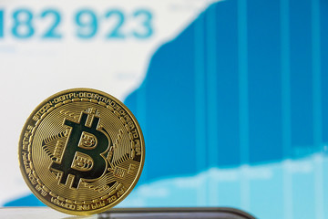 Coin Bitcoin on a background of blue graphics close-up. concept of an uptrend or an downtrend, cryptocurrency news. fluctuations and forecasting of exchange rates of virtual money bitcoin.