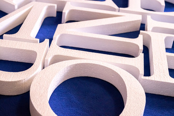 white letters cut out of foam without painting on a blue background. blank for decoration, logo making