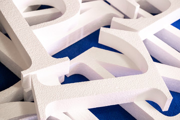 white letters cut out of foam without painting on a blue background. blank for decoration, logo...