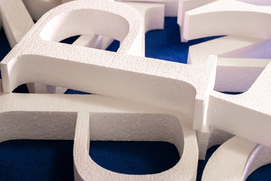 white letters cut out of foam without painting on a blue background. blank for decoration, logo making