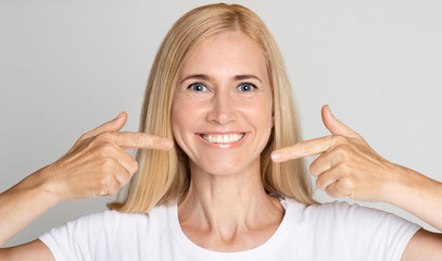 Strong healthy teeth. Woman pointing on her perfect smile