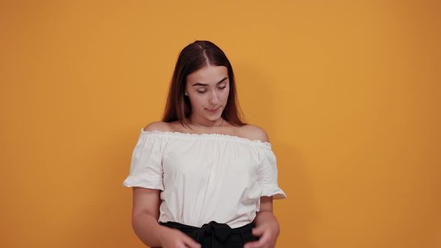 Sick young woman keeping hand on head, headache isolated on orange background in studio in casual white shirt. People sincere emotions, lifestyle concept.
