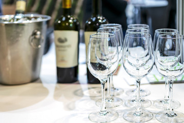 Row of shining wine glasses with wine bottles on the background in the restaurant ( copy space)