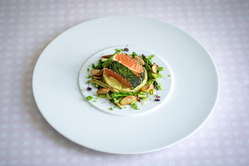 Salmon with Dill  and Sauteed Vegetables served on white plate over white texture background. Top view, copy space. Plating, fine dining